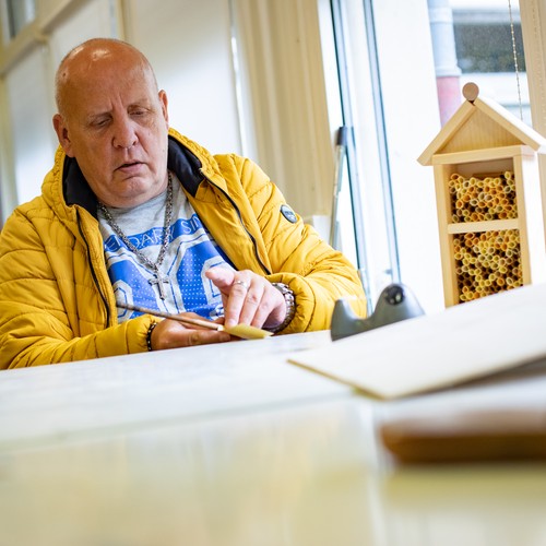 Eine leistungsberechtigte Person in der Tagesstätte beim Bau eines Insektennistkasten.