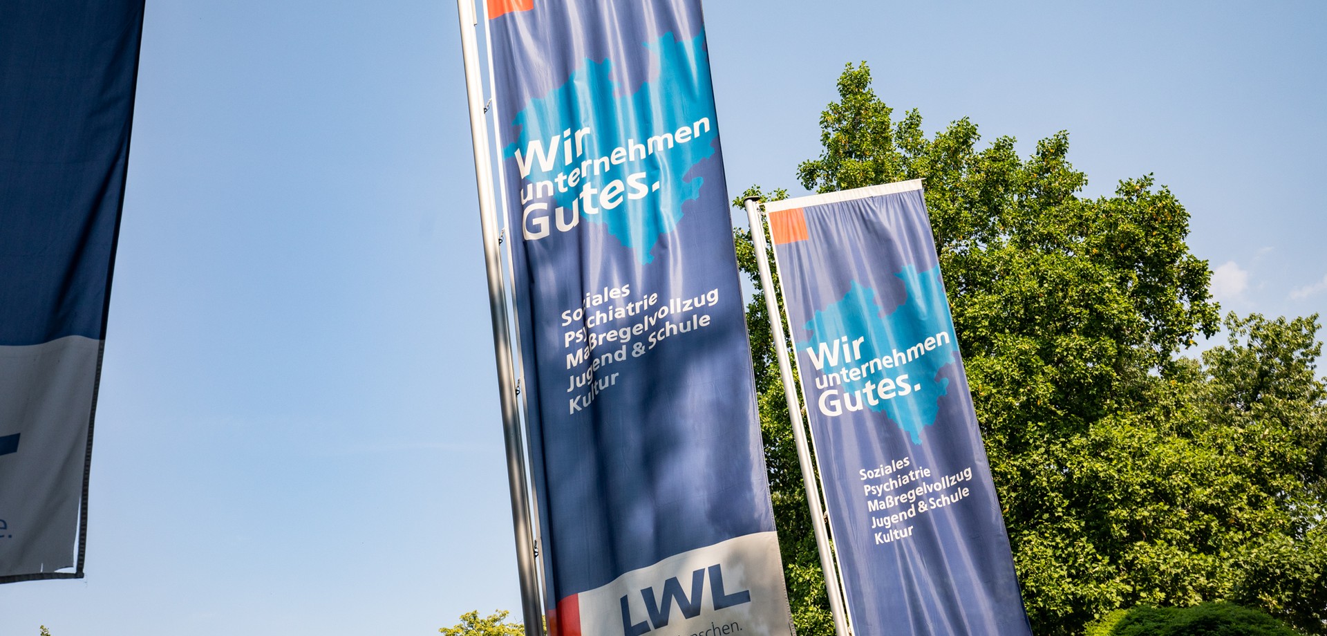 Zwei LWL-Fahnen mit der Aufschrift: Wir unternehmen Gutes.