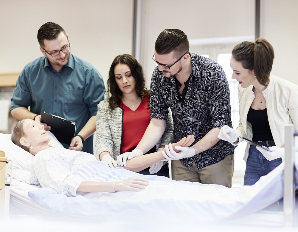 Das Foto zeigt schematisch eine praktische Lehreinheit am Krankenbett.