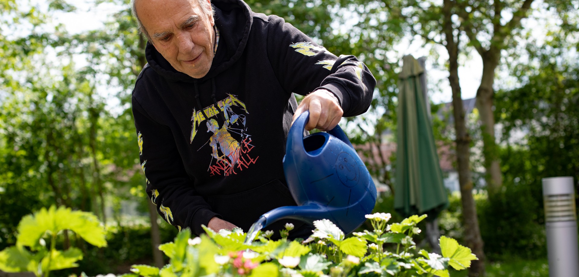 Eine leistungsberechtigte Person gießt das Kräuterbeet im Garten des Wohnhauses in Geseke.