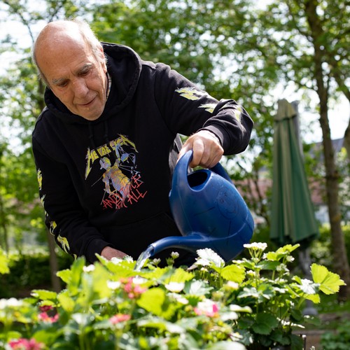 Eine leistungsberechtigte Person gießt das Kräuterbeet im Garten des Wohnhauses in Geseke.