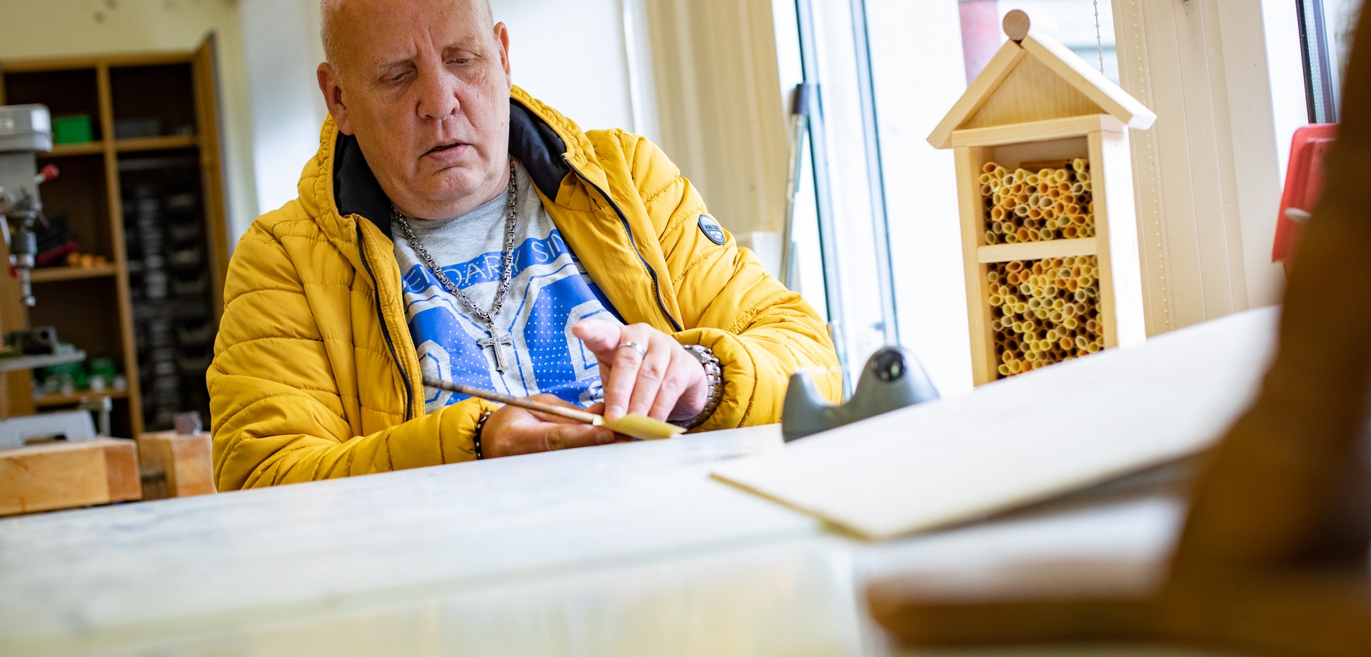 Eine leistungsberechtigte Person der Tagesstätte beim Bau eines Insektennistkasten.