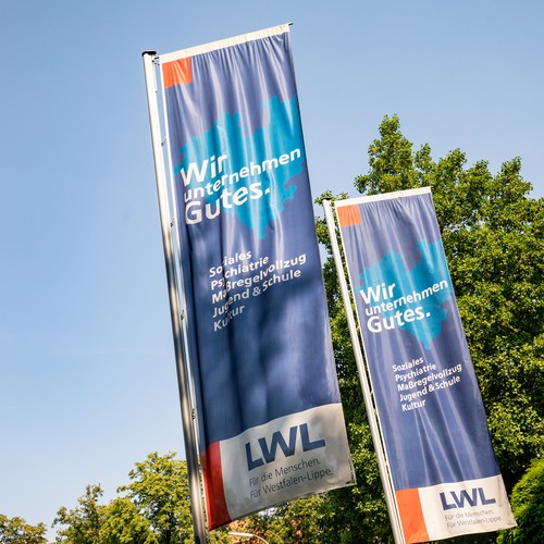 Zwei LWL-Fahnen mit der Aufschrift: Wir unternehmen Gutes.